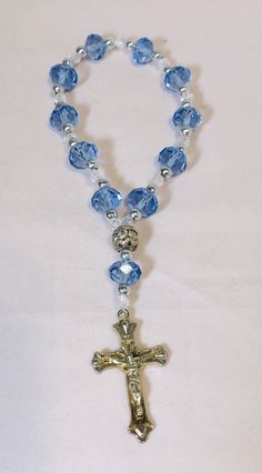 6” Rosary Overflowing Blue-Transparent Multifaceted Glass Beads and Crucifix This beautiful 6-inch bracelet is perfect for any occasion, whether it's Mother's Day, Christmas, birthdays, Valentine's Day, or Confirmation/Communion. The bracelet features 11 stunning blue and multicolored glass beads in a round shape, each measuring .375 inches in width, and one metal bead. The 11 blue beads are multifaceted, adding an extra touch of elegance. The bracelet also has a charming crucifix as a centerpiece, to complete the religious theme. It is held all together by elastic material for a comfortable fit making it easy to slip-on and pull-off. This item is perfect for those who love religious-themed jewelry and makes a great gift. Rosary stretch bracelet, with blue main beads with silver beads in b Rosary Bracelet Diy, Diy Rosary Necklace, Rosary Ideas, Diy Rosary, Beautiful Rosaries, Catholic Rosary Bracelet, Anglican Rosary, Chaplet Rosary, Mini Rosaries