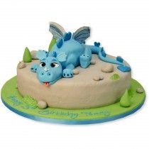 a birthday cake with a blue dragon laying on it's side and green trimmings