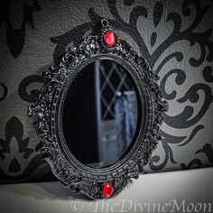 a mirror with some red beads on the bottom of it and a black wall behind it