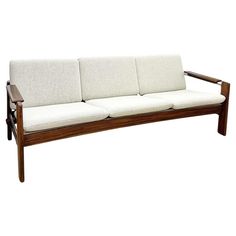 a wooden couch with white cushions on it's back end and armrests