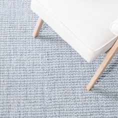 a white chair sitting on top of a blue carpet next to a wooden legrest