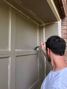 a man is painting the side of a garage door