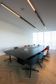 an empty conference room with wooden floors and white walls, along with black tables and chairs