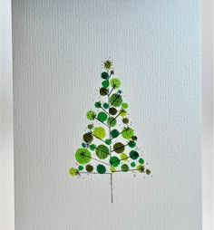 a christmas tree made out of green leaves on a white card with watercolors