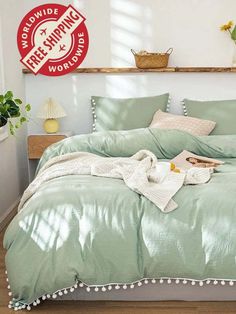 a bed with green comforter and pillows in a room next to a wooden shelf