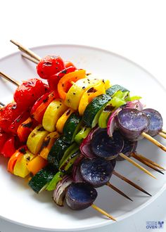 several skewers of colorful vegetables on a white plate