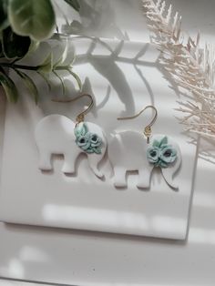 two elephants with flowers on them are sitting next to a plant and a white plate