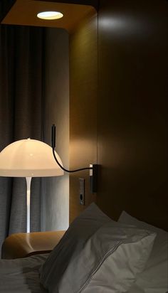 a lamp is on in the corner of a room next to a bed with white sheets and pillows