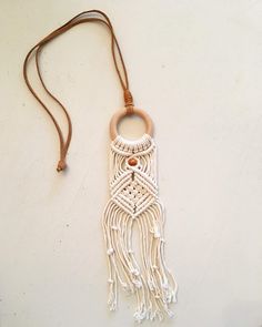 a white macrame necklace hanging on a brown cord