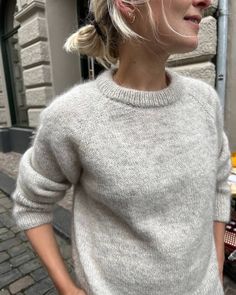 a woman with blonde hair wearing a gray sweater