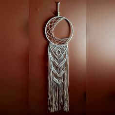 a white macrame hanging on the wall with a crescent shaped object attached to it