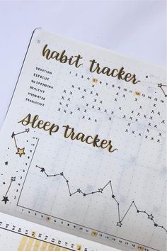 an open planner with the words habit tracker and sleep tracker written in gold on it