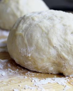 two uncooked doughnuts sitting on top of a wooden table next to flour