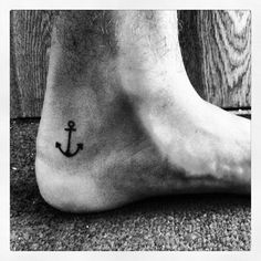 a black and white photo of a person's foot with an anchor tattoo on it