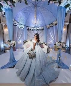 a woman in a blue dress sitting on a white chair with flowers around her neck