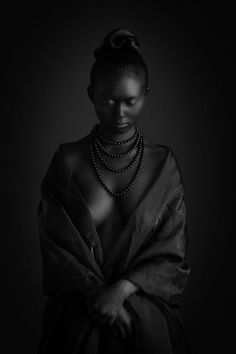 a woman in a black dress with pearls on her neck