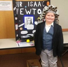 a young boy wearing a paper crown standing in front of a bulletin board