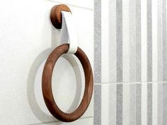 a wooden ring hanging on the wall next to a white and gray tiled bathroom stall