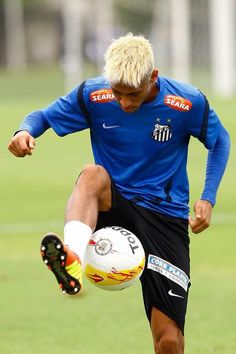 a man kicking a soccer ball on top of a field