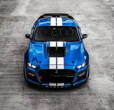 a blue sports car with white stripes parked in a parking lot