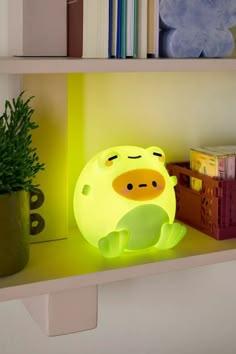 a yellow lamp sitting on top of a shelf next to a green potted plant