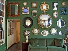 a living room filled with green couches and mirrors on the wall next to a doorway