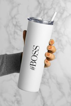 a woman's hand holding a white tumbler cup with the word boss on it