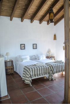 two beds sitting in a bedroom next to each other on top of a tiled floor