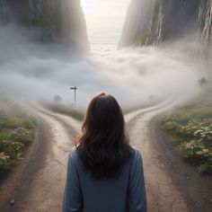 a woman standing in the middle of a dirt road with fog rolling over her head