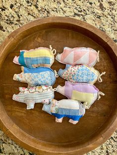 four small stuffed animals in a wooden bowl