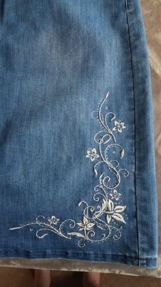 someone is showing off their jeans with embroidered flowers on them, and the bottom part of it