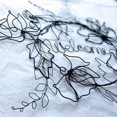 wire work with the word smell written on it and leaves attached to them, sitting on a piece of white paper