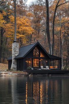 a house sitting on top of a lake next to trees with fall foliage in the background