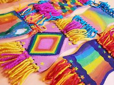 several colorful pieces of cloth with fringes and beads on top of each other, all in different colors