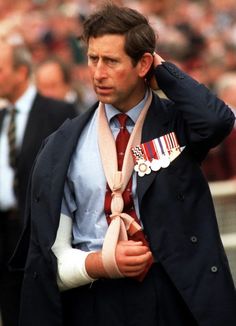 a man in a suit and tie is holding his hand on his head while walking