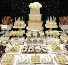 a table topped with lots of desserts covered in white frosting and gold decorations