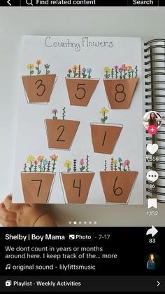 someone is holding up a book with numbers and flowers on it in front of them