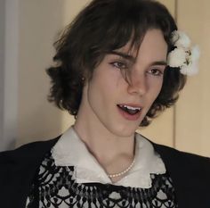 a young woman wearing a black and white dress with a flower in her hair is looking at the camera