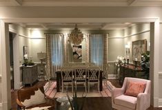 a living room filled with furniture and a chandelier hanging from the ceiling over a wooden table