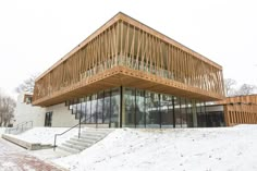 a wooden building with glass windows and stairs in the snow