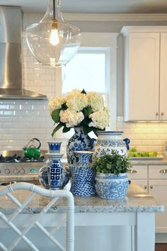 a kitchen with white cabinets and blue and white vases on the counter, along with an island