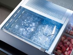 an open refrigerator with ice and strawberries in the freezer door, on display