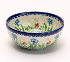 a blue and white bowl with flowers painted on the side, sitting in front of a white background