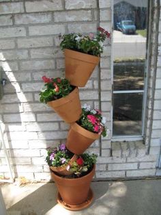 four flower pots stacked on top of each other in front of a brick building with the door open