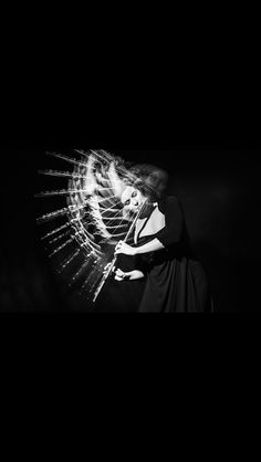 a black and white photo of a woman with her hands on her hips, in front of a dark background