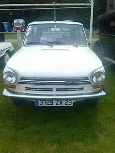 an old white car is parked in the grass