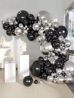 black and silver balloons in the shape of an o on a floor next to a window