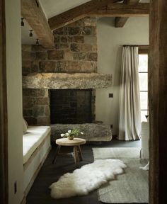 a living room with stone fireplace and white fur rugs