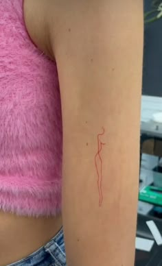 a woman's arm with a red line tattoo on her left arm, and a pink top