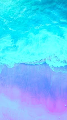 an aerial view of the ocean with pink and blue waves coming in from the shore